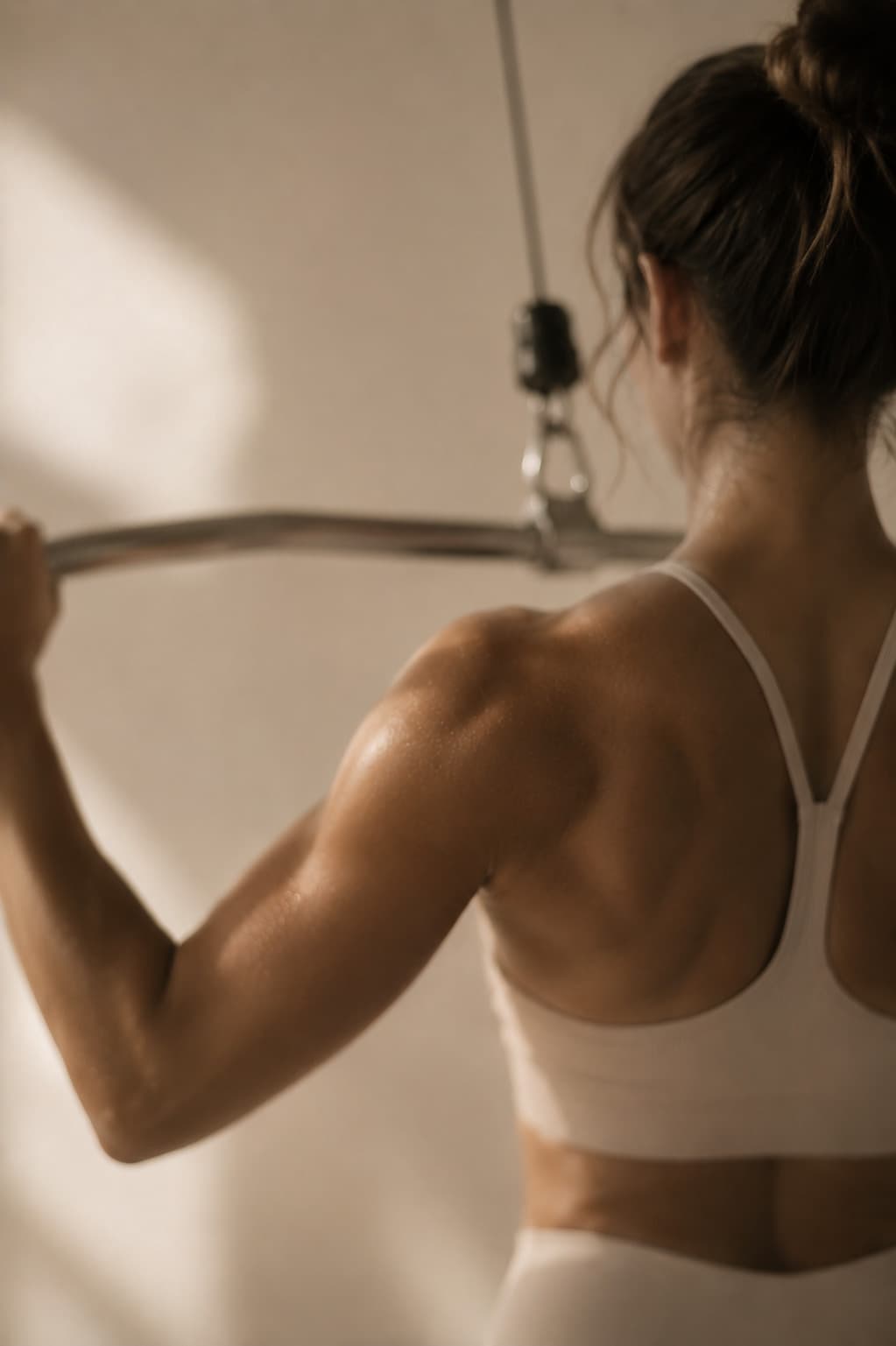Mujer entrenando dorsales en polea alta